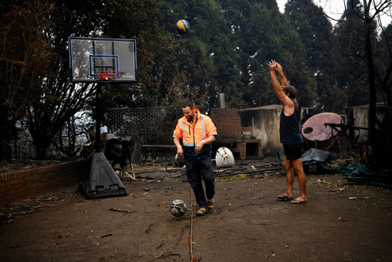 سكان كوبارجو يلعبون كرة السلة بجانب منزلهم المحترق