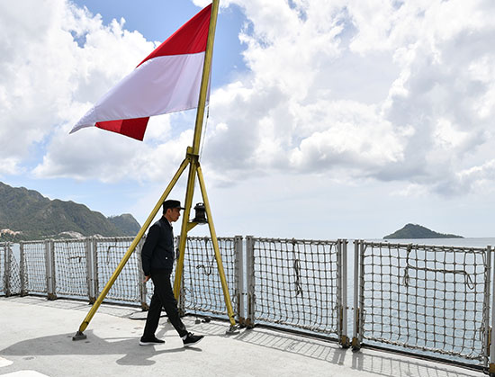 الرئيس الإندونيسى جوكو ويدودو يسير بجوار العلم الوطني أثناء زيارته لقاعدة عسكرية