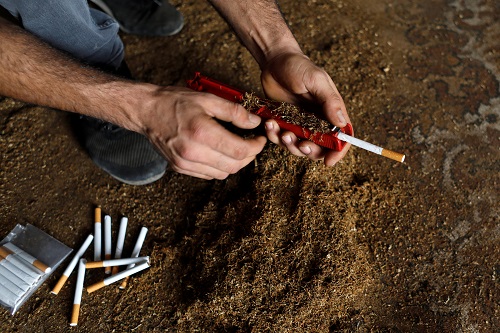 عامل فلسطيني يملأ سيجارة بالتبغ المزروع محليًا