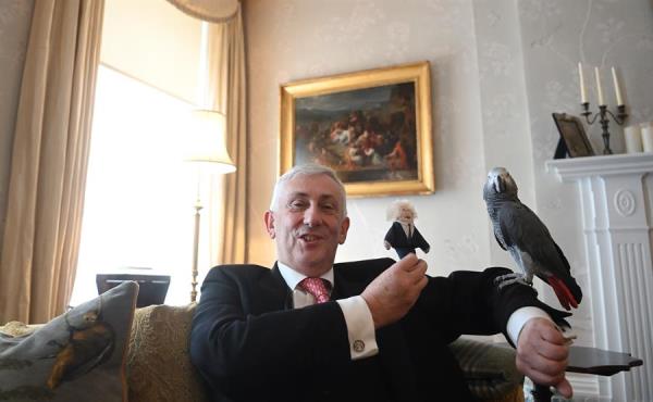 رئيس مجلس العموم البريطاني يحمل دمية ومعه ببغائه بوريس