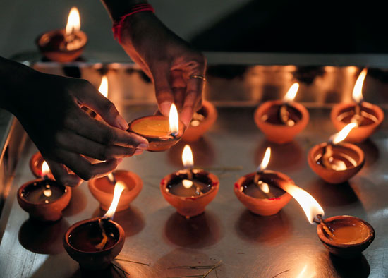 أحد المصلين يضيء مصباح زيت في معبد هندوسي