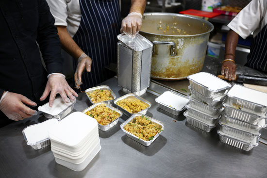 يعد الموظفون وجبات الطعام للتبرع بها للمشردين والمحتاجين  (1)