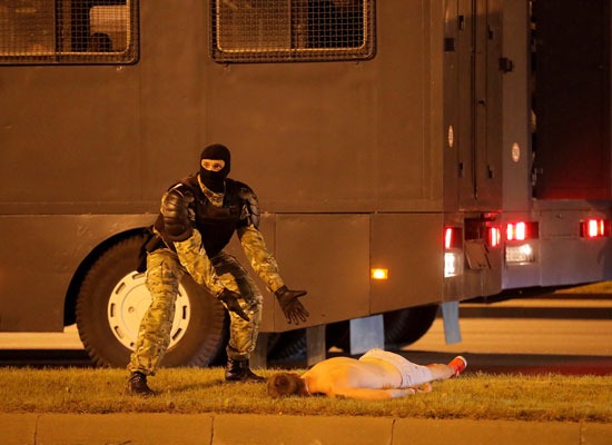 ضابط في بيلاروسيا بجانبه متظاهر مصاب