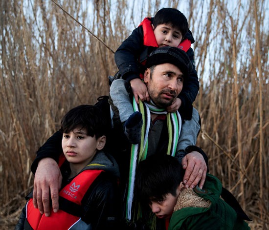 رجل يحمل أبنائه الثلاثة أثناء وصول المهاجرين من أفغانستان
