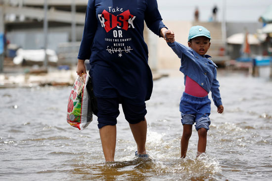 امرأة وطفلها يسيران عبر المياه في ميناء كالي أدم