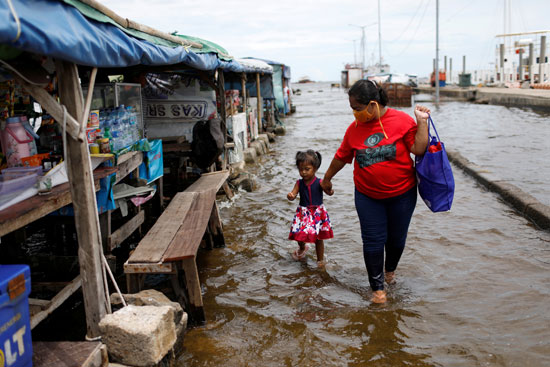 طفلة مع والدتها يسيران بعد فيضان الميناء