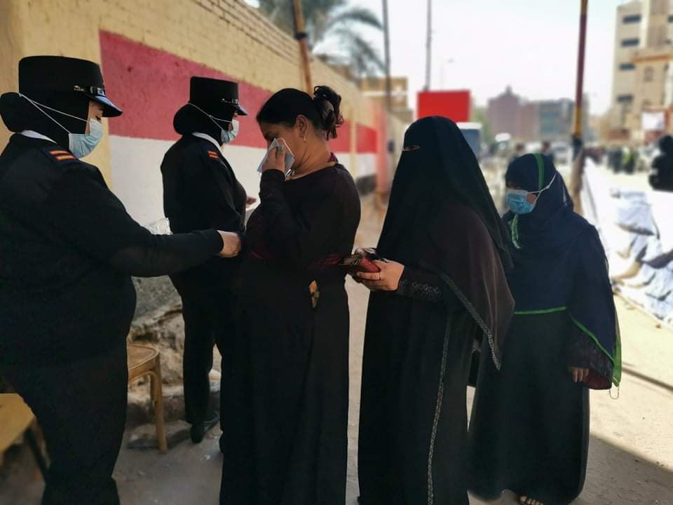 الشرطة توزع الكمامات على الناخبين فى لجان أسوان
