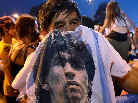 رجل يحمل قميص عليه صورة مارادنا