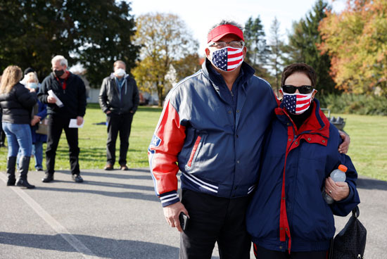 زوجان يرتديان كمامات بعلم امريكا فى مركز اقتراع