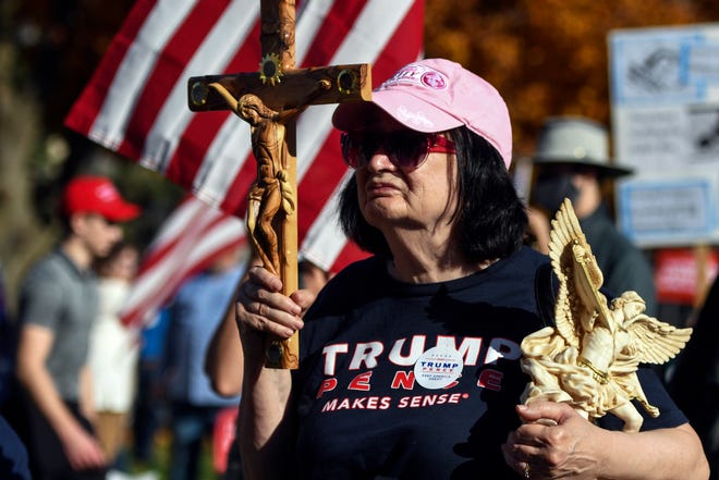 إحدى مؤيدى ترامب تحمل الصليب فى مدينة لانسنج بولاية ميتشيجان