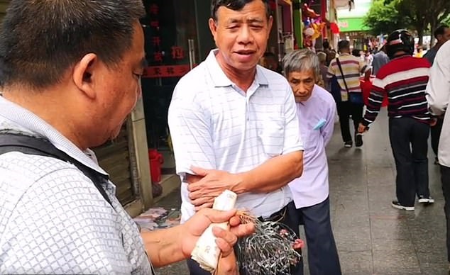 رجل صيني يسير بفأرين في سوق مربوطين من أفواههم (4)