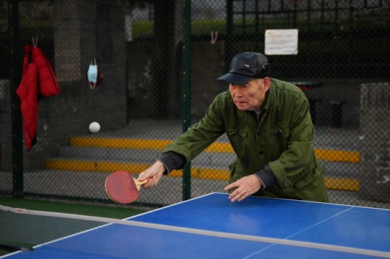 رجل مسن يلعب تنس الطاولة في حديقة في بكين