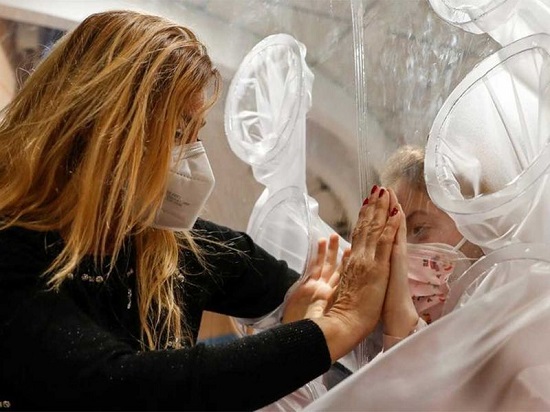 طفلة في المستشفى تلامس يد أمها من خلال غطاء بلاستيكي