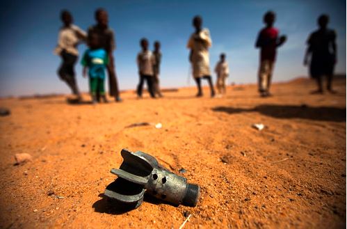 أطفال يقفون بجانب بقايا قذيفة هاون تم التخلي عنها مؤخرًا في مخيم العباسي للنازحين داخليًا ، في مليط ، شمال دارفور
