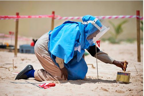 عضوة في فريق التخلص من الذخائر المتفجرة تنظف الرمال من قذيفة هاون خلال الأعمال المتعلقة بالألغام في مقديشو ، الصومال