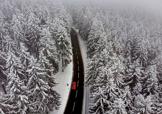 سيارة تسير بين الأشجار المغطاة بالثلوج في منطقة تاونوس بالقرب من فرانكفورت