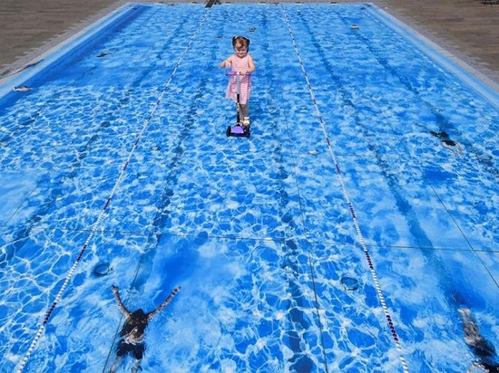 طفلة تسير فوق لوحة فنية لحمام سباحة