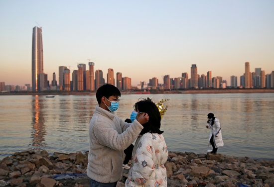 شاب يلبس صديقته الكمامة في الاحتفالات بالصين