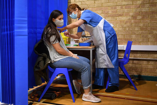 ممرضة تقدم لقاح Pfizer  BioNTech COVID-19 لامرأة في مركز التطعيم في كارديف