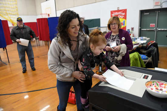 إمرأة تحمل إبنتها الصغيرة أثناء التصويت فى الانتخابات التمهيدية الأمريكية