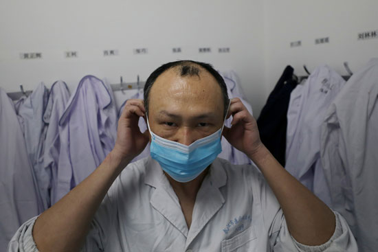 عامل بمستشفى بمدينة ووهان يرتدى قناع الوجه