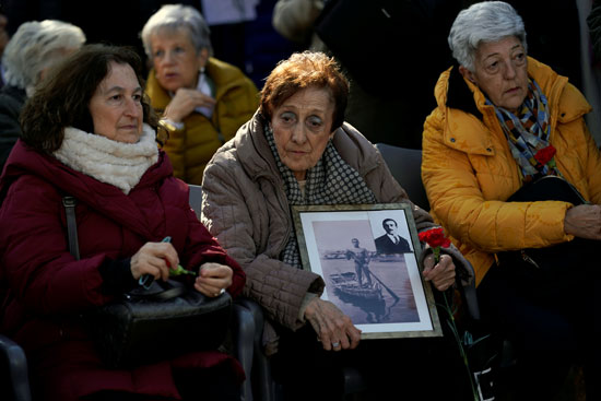 ميلاجروس مارتينيز تحمل صورة لوالدها وابنها أثناء دفن