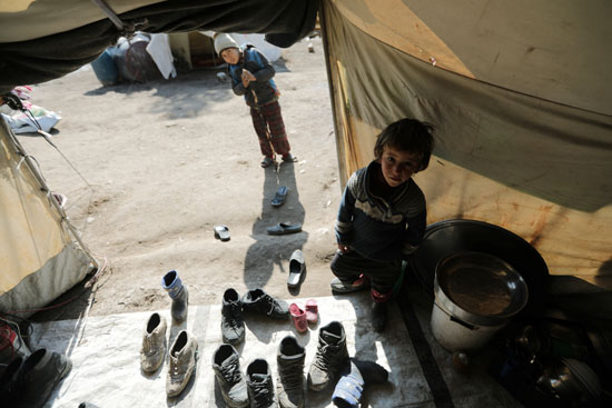 طفل من النازحين داخلياً يقف داخل خيمة في قرية قطمة