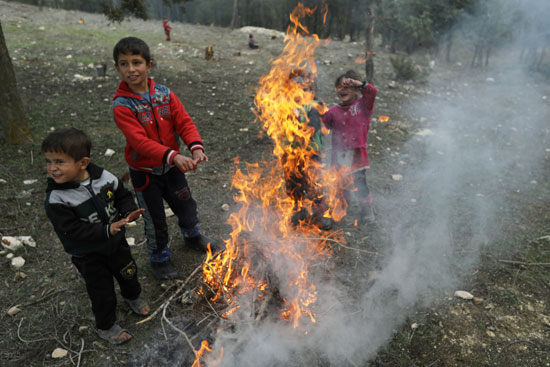 أطفال مشردون داخليًا يسخنون أنفسهم حول حريق في قرية القطمة