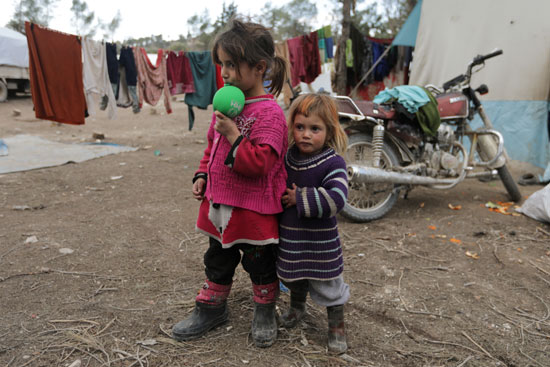 أطفال مشردون داخليا يقفون خارج الخيام في مخيم مؤقت في قرية القطمة