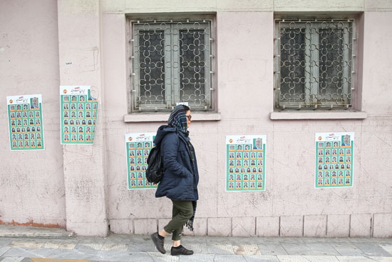 مواطنة إيرانية تسير بجوار الدعاية دون أن تلتفت لها