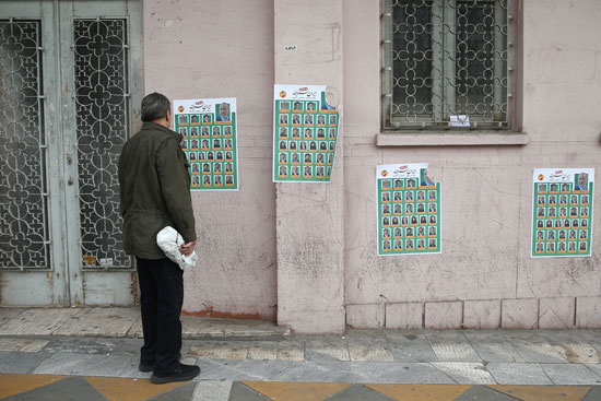 مواطن إيران ينظر إلى ملصقات بالشوارع