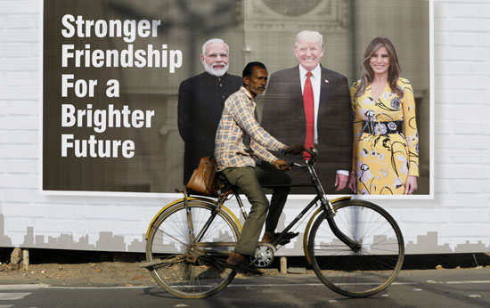 رجل يمر بدرجة من أمام صورة ترامب وايفانكا والرئيس الهندى