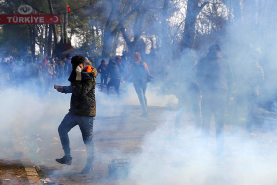 مهاجر يرمي أسطوانة غاز مسيل للدموع مرة أخرى خلال اشتباكات مع الشرطة اليونانية