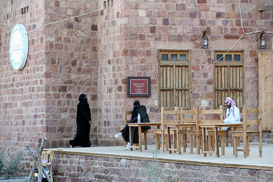 زوار يجلسون في مقهى في البلدة القديمة خلال مهرجان تانتورا في العلا
