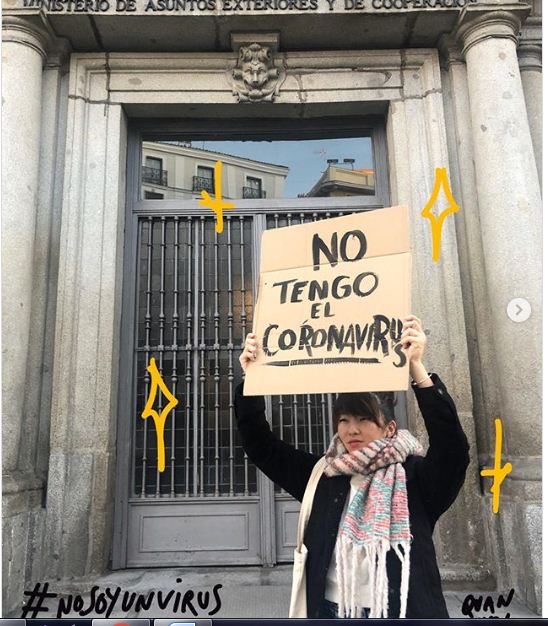 فتاة صينية فى اسبانيا تحمل لافتة  انا لا احمل فيروس كورونا