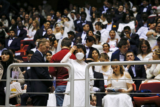 الأزواج الذين يرتدون أقنعة للحماية من فيروس كورونا  خلال حفل زفاف جماعي للكنيسة الموحدة