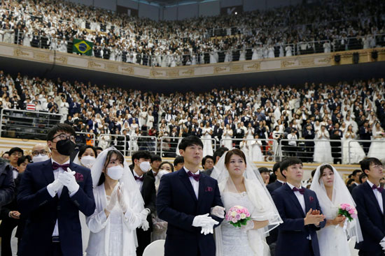 الأزواج الذين يرتدون أقنعة للحماية من فيروس كورونا الجديد خلال حفل زفاف جماعي للكنيسة الموحدة