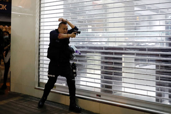 ضابط يصوب مسدسه نحو المتظاهرين