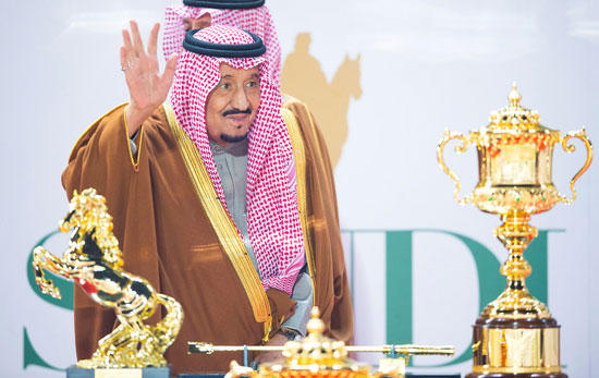 يقف العاهل السعودي سلمان بن عبد العزيز بالقرب من كأس الفائز وهو يحضر السباق النهائي لكأس السعودية