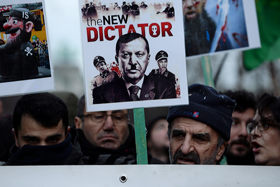 متظاهر يحمل لافتة تصور الرئيس التركي رجب طيب أردوغان خلال مظاهرة مناهضة لزيارة الرئيس ، بالقرب من ميدان شومان في بروكسل