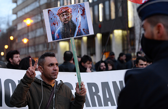 متظاهر يحمل لافتة تصور الرئيس التركي يتظاهر ضد زيارة الرئيس قرب ميدان شومان في بروكسل