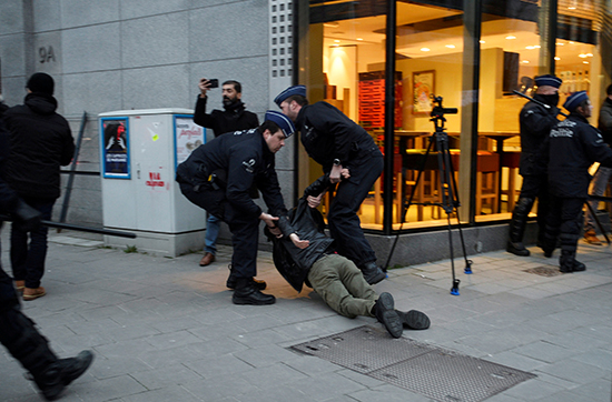 ضباط الشرطة يحتجزون متظاهرًا خلال احتجاج على زيارة الرئيس التركي رجب طيب أردوغان قرب ميدان شومان في بروكسل