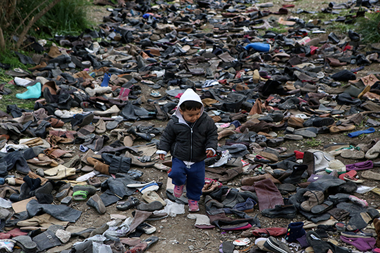 صبي يمشي بين أزواج من الأحذية بجوار مخيم موريا للاجئين والمهاجرين في جزيرة ليسبوس
