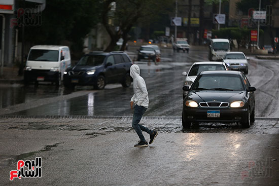 مواطن يعبر الطريق وسط الامطار