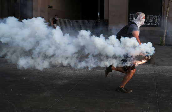 متظاهر يقذف بقنبلة الدخان