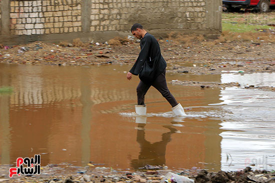 شاب يعبر مياه الامطار المتراكمه