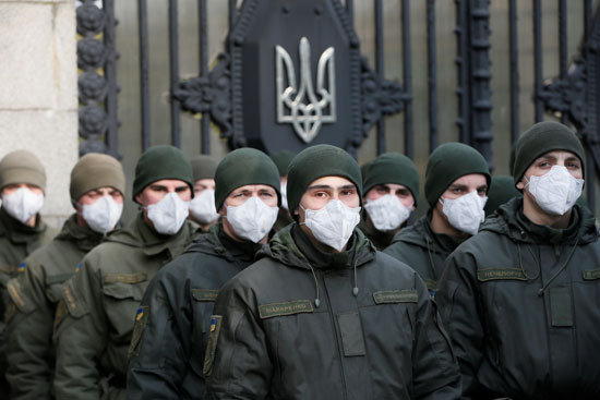 أعضاء-الحرس-الوطني-لأوكرانيا-يرتدون-أقنعة-واقية-يقفون-حراسة-أمام-مبنى-البرلمان-الأوكراني-في-كييف