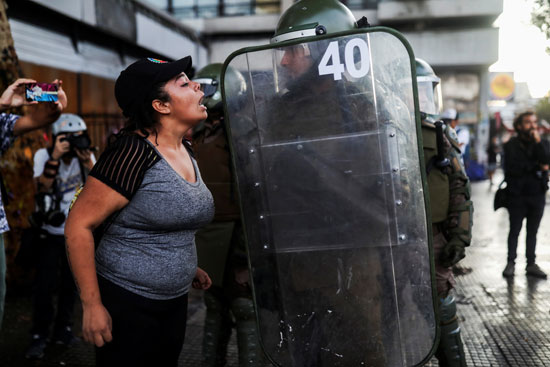 امرأة تتجادل مع شرطي مكافحة الشغب خلال احتجاج ضد حكومة تشيلي