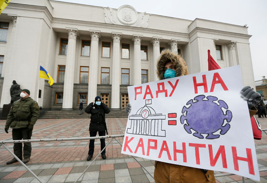 ناشط-يحمل-ملصقًا-خلال-مسيرة-تطالب-بعزل-المشرعين-في-كييف