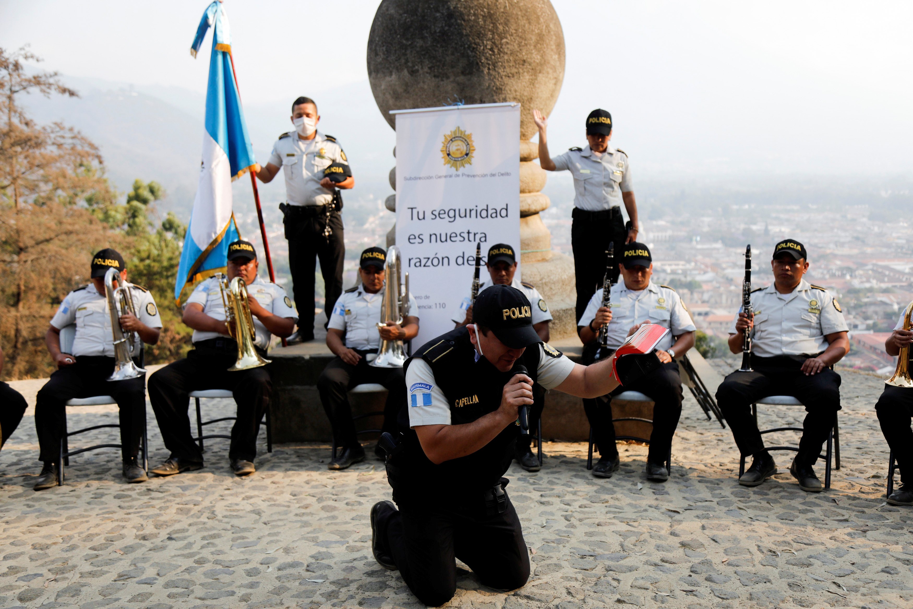 ضابط شرطة يصلي أثناء أداء فرقة الشرطة الموسيقية في سيرو دي لا كروز  في مدينة جواتيمالا